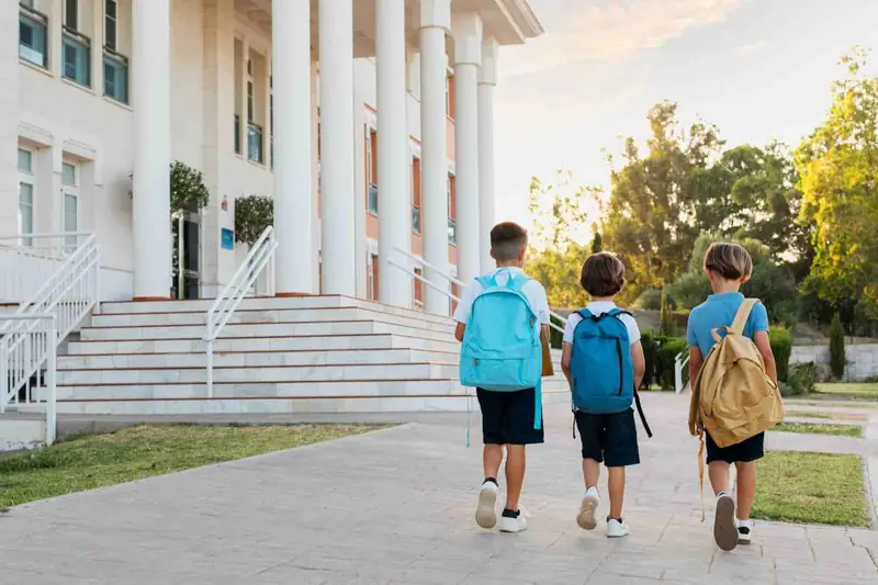 Children with school bags walking up to a school entrance